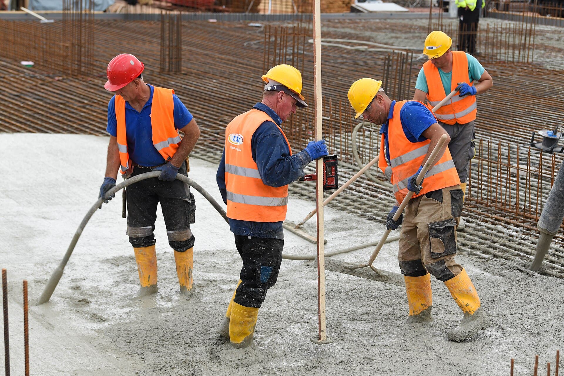 Construction crew pouring and finishing concrete over steel reinforcement