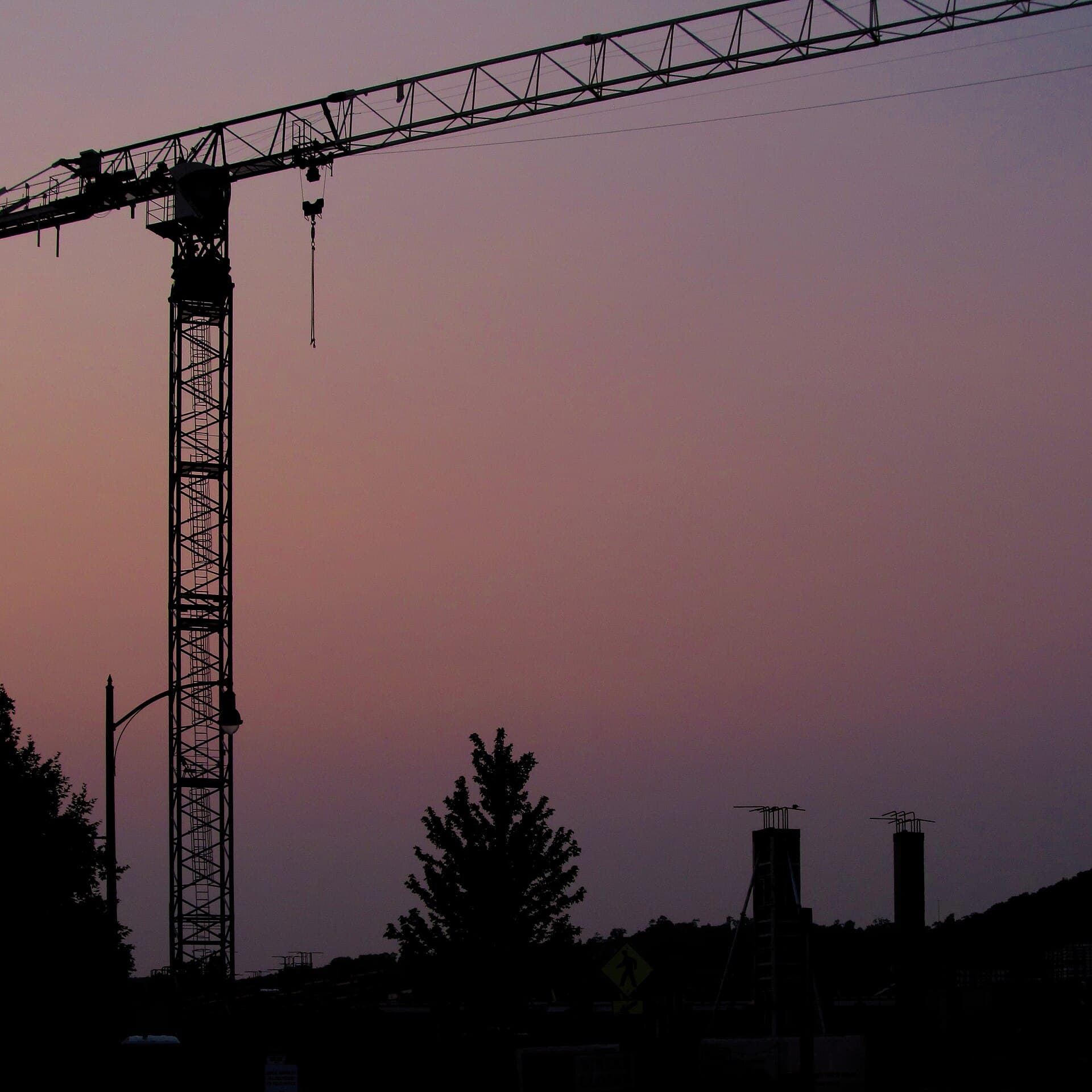 Tower crane silhouetted against a violet dusk sky
