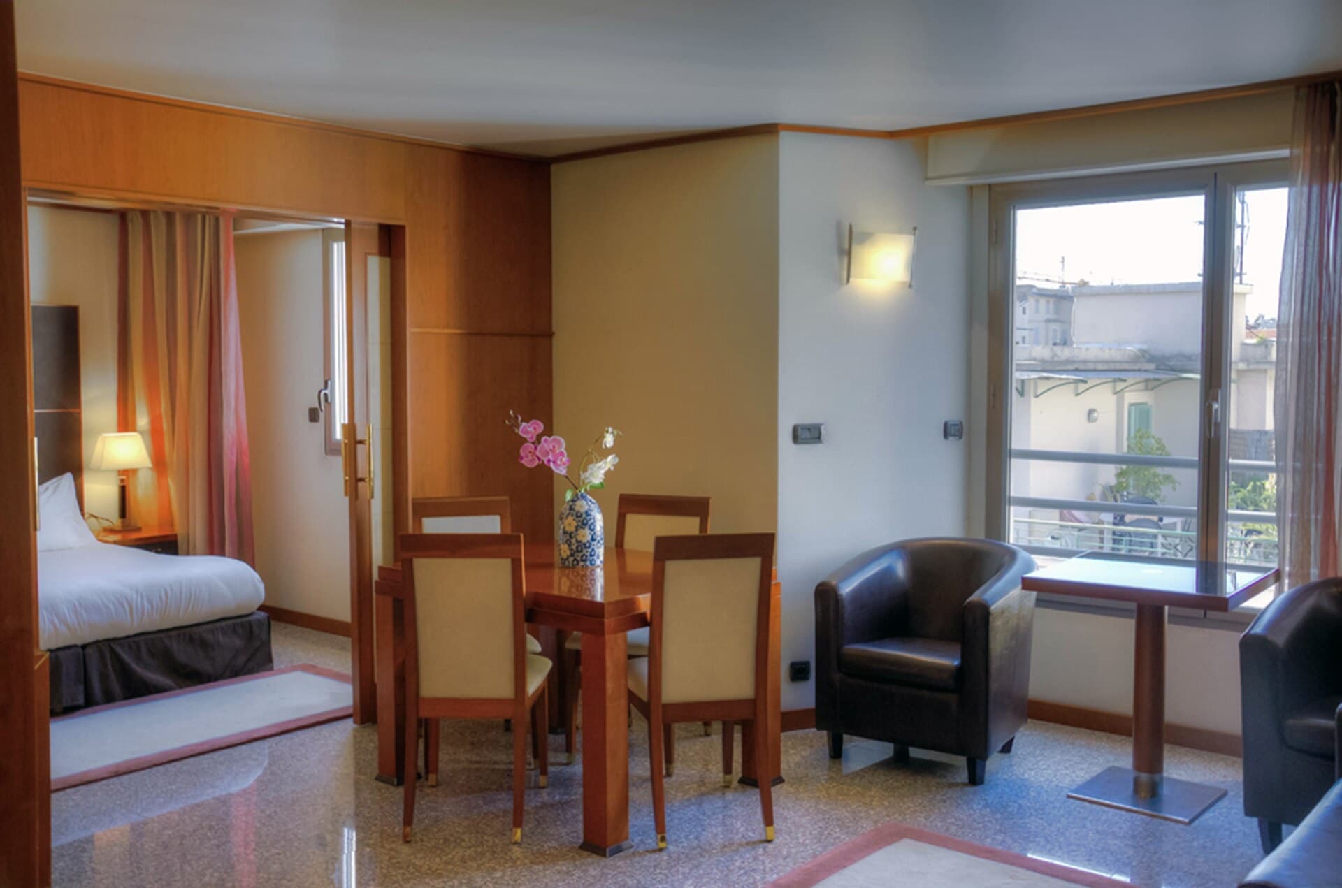 Warm wood-panelled hotel suite with dining area and bedroom
