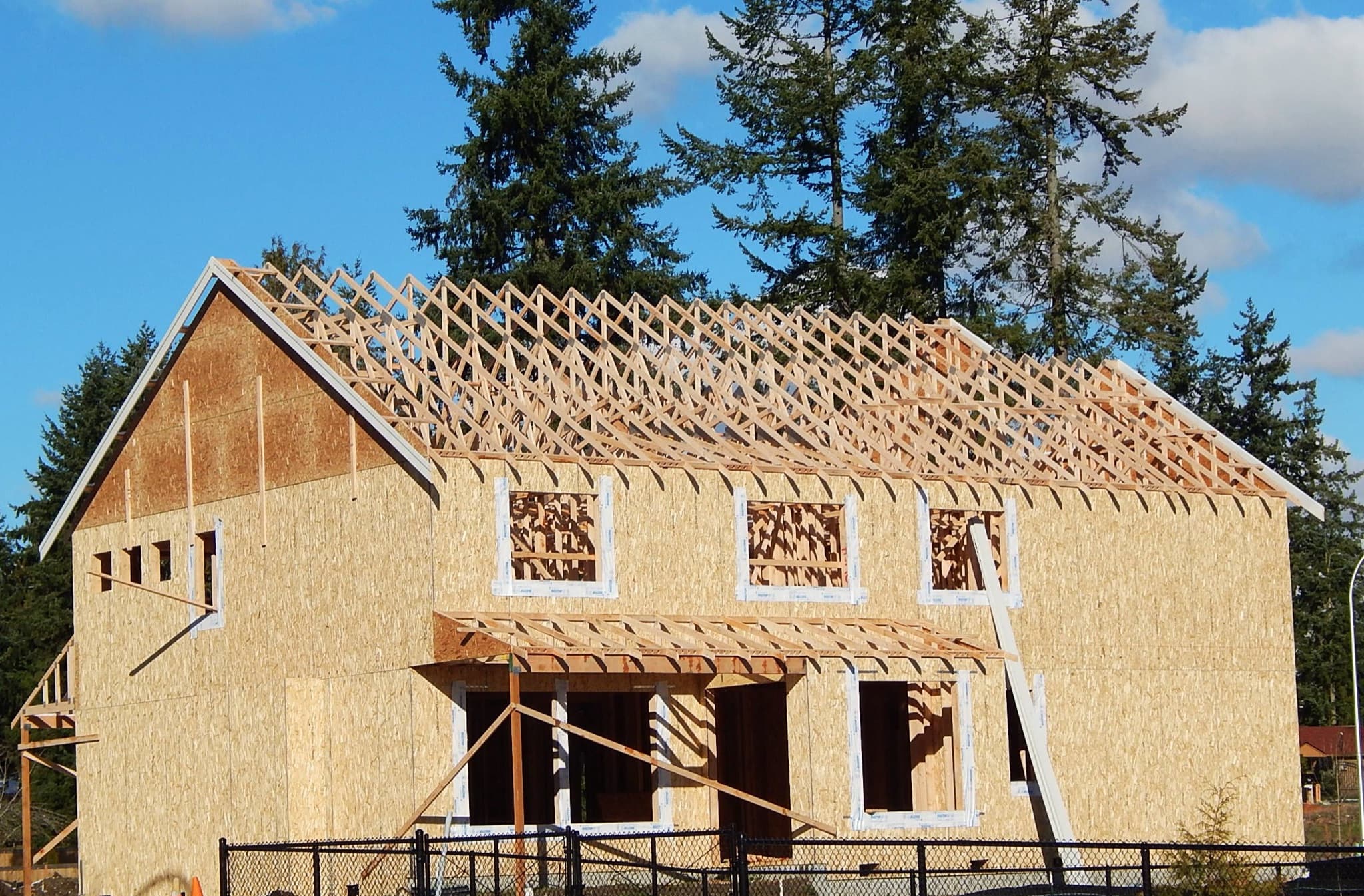 Two-story family home under construction with fresh wood framing and roof trusses