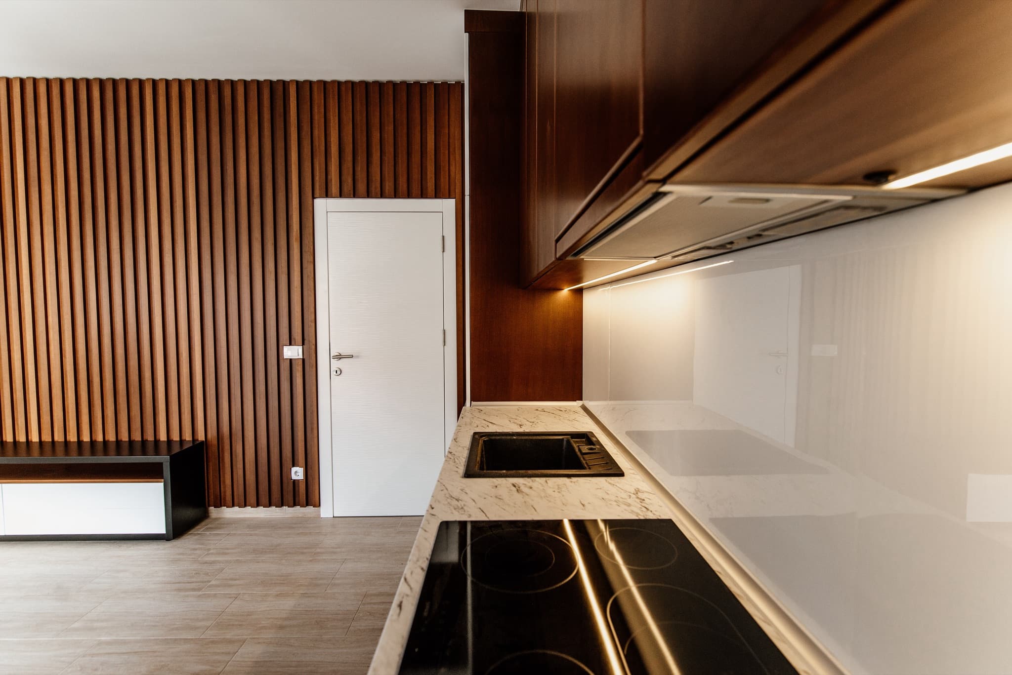 Newly fitted-out modern interior with walnut wood paneling and a marble kitchen counter