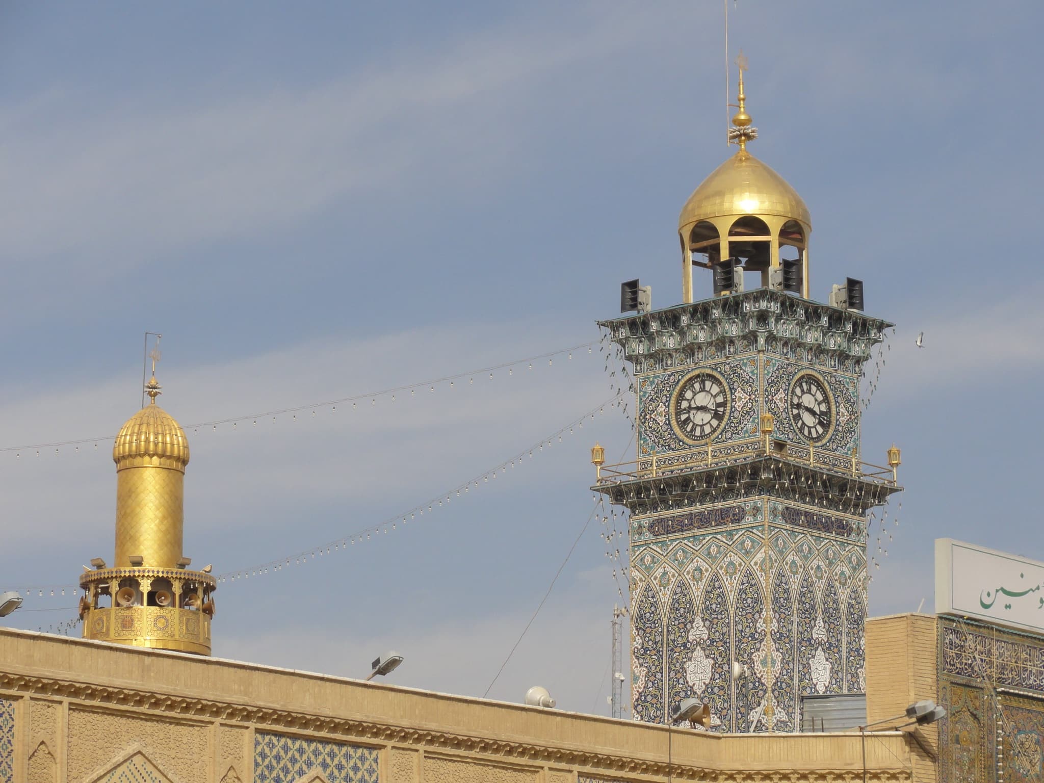 Golden dome and tiled clock tower in the shrine district of Najaf