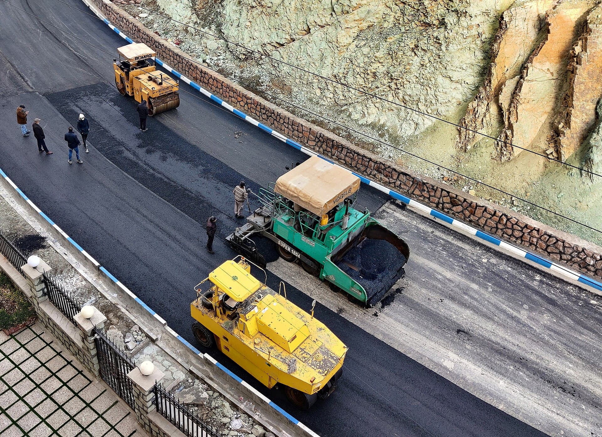 Asphalt paving machines and crew resurfacing a road
