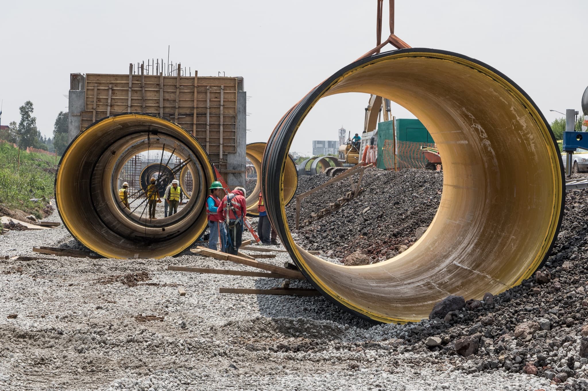 Crews installing large-diameter water pipes on an open worksite