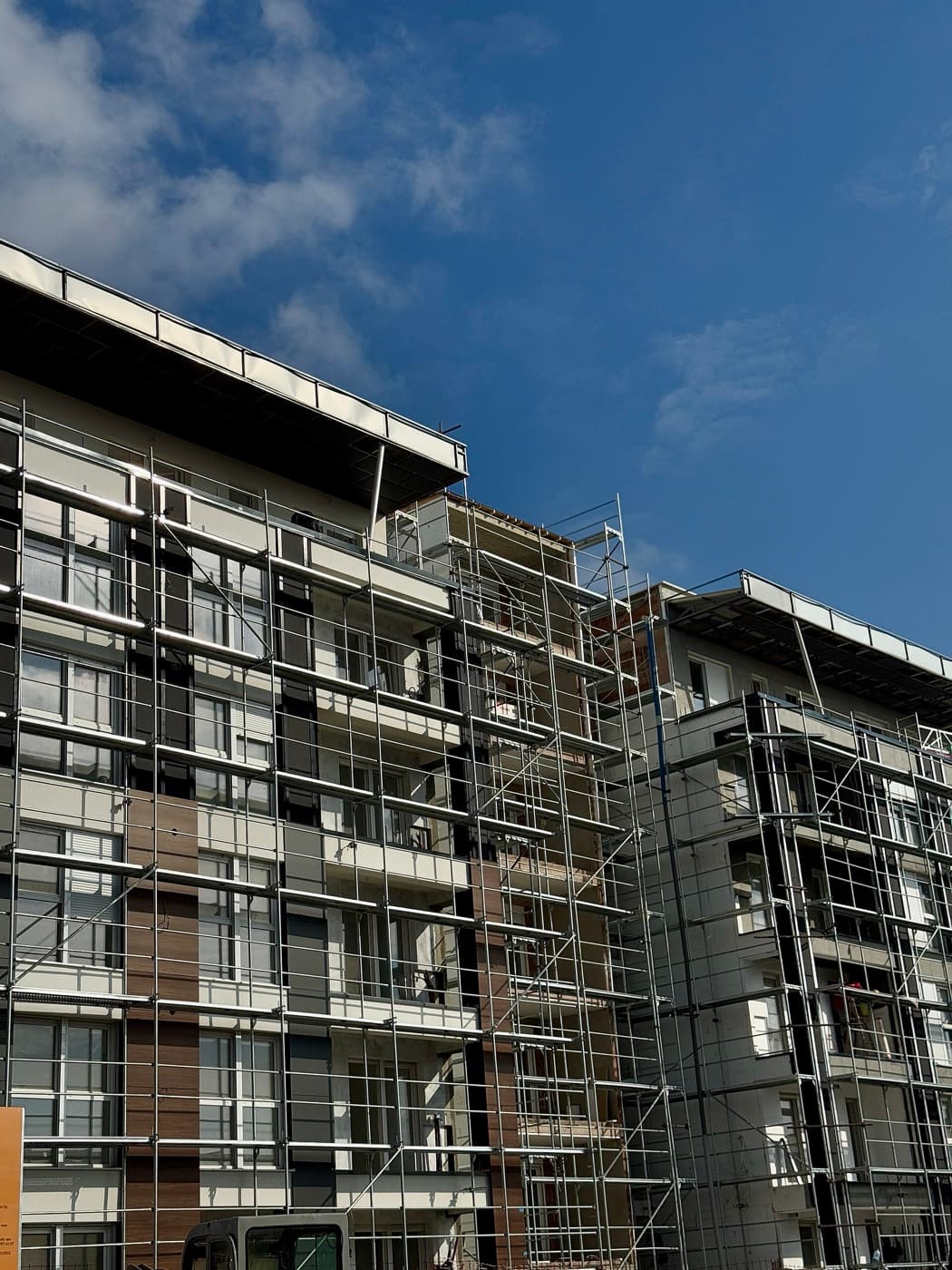 Residential building wrapped in scaffolding under a clear blue sky