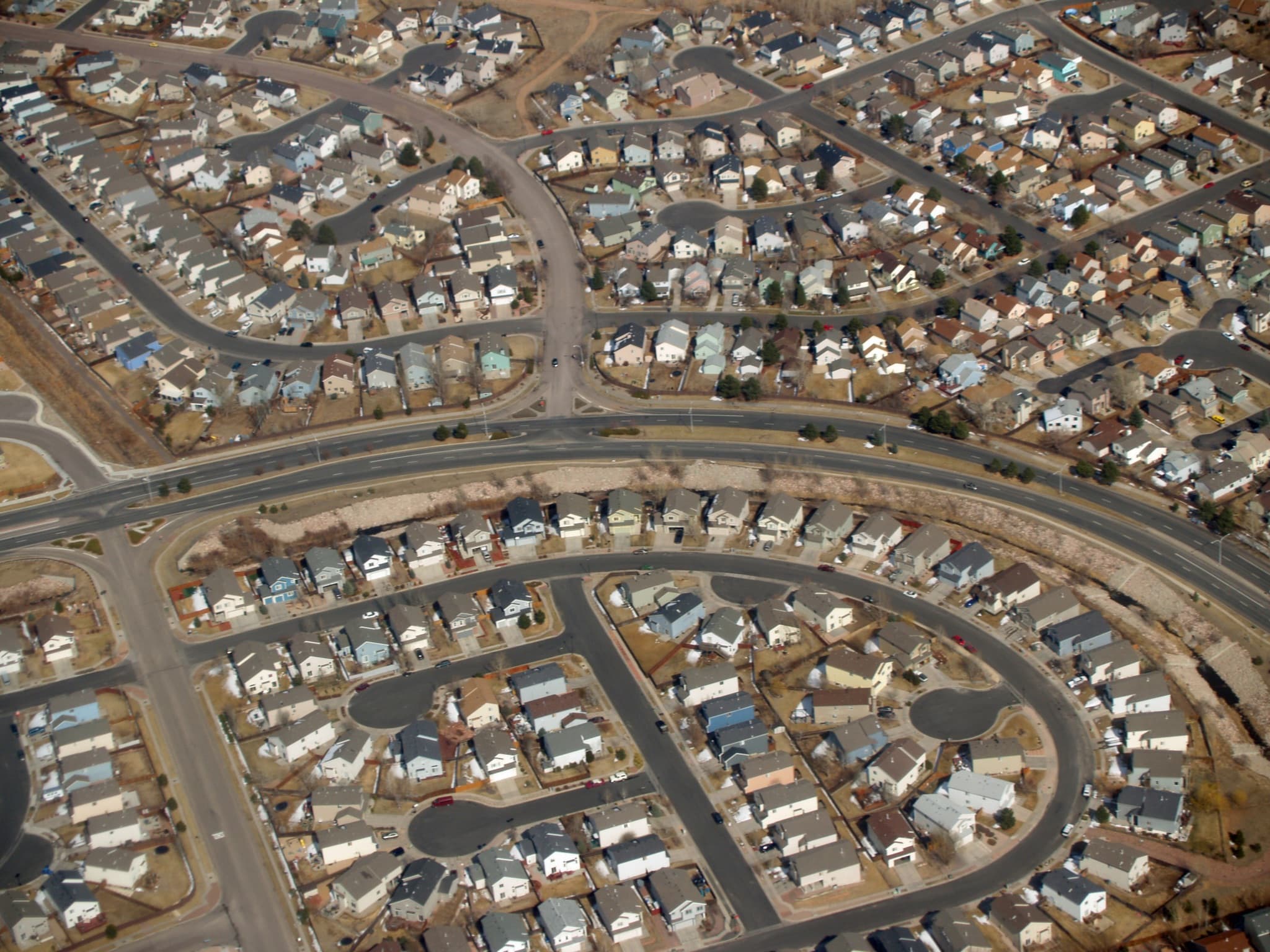 Aerial view of a suburban neighborhood with rows of matching single-family homes on curving streets