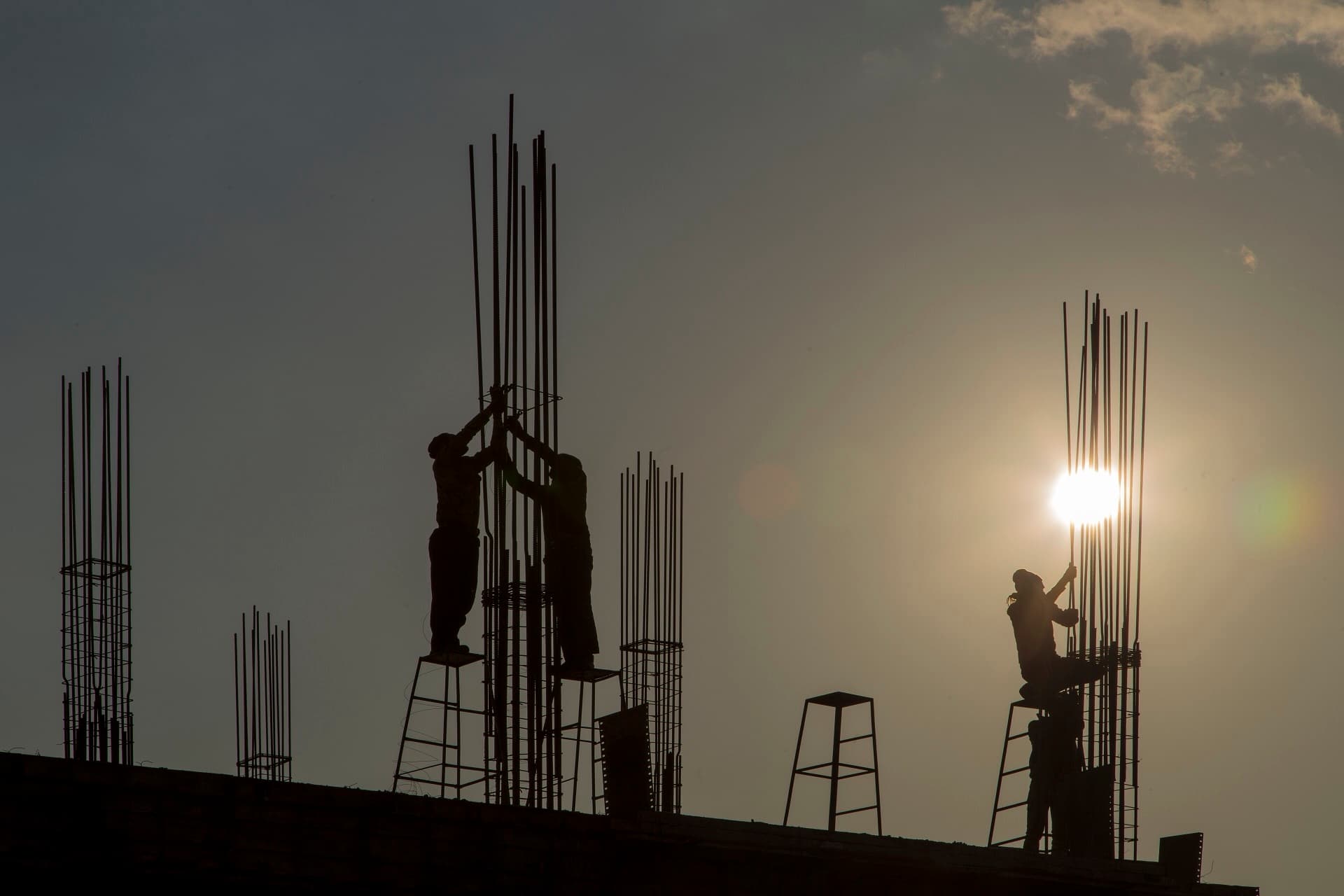 Ironworkers silhouetted against the setting sun while tying rebar columns